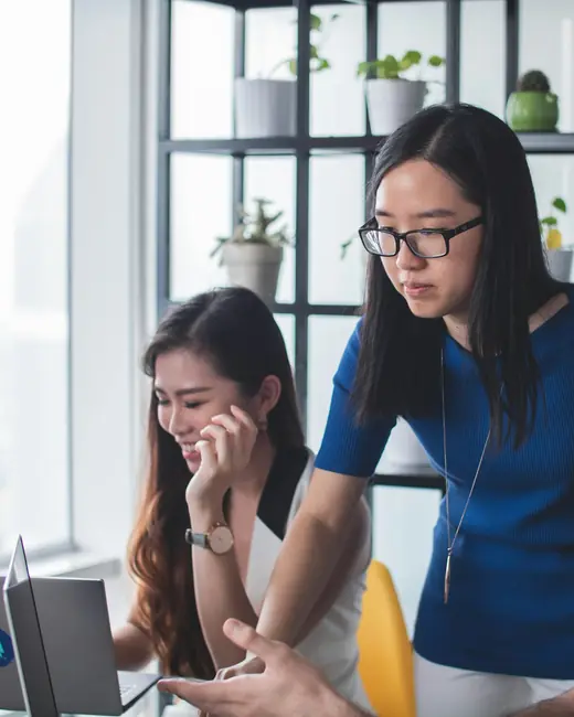 Deux jeunes femmes travaillent ensemble devant un ordinateur portable.
