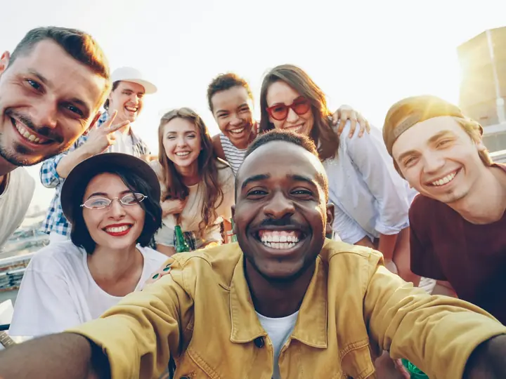 Une dizaine de jeunes de différentes origines rient ensemble sur un toit, en ville.